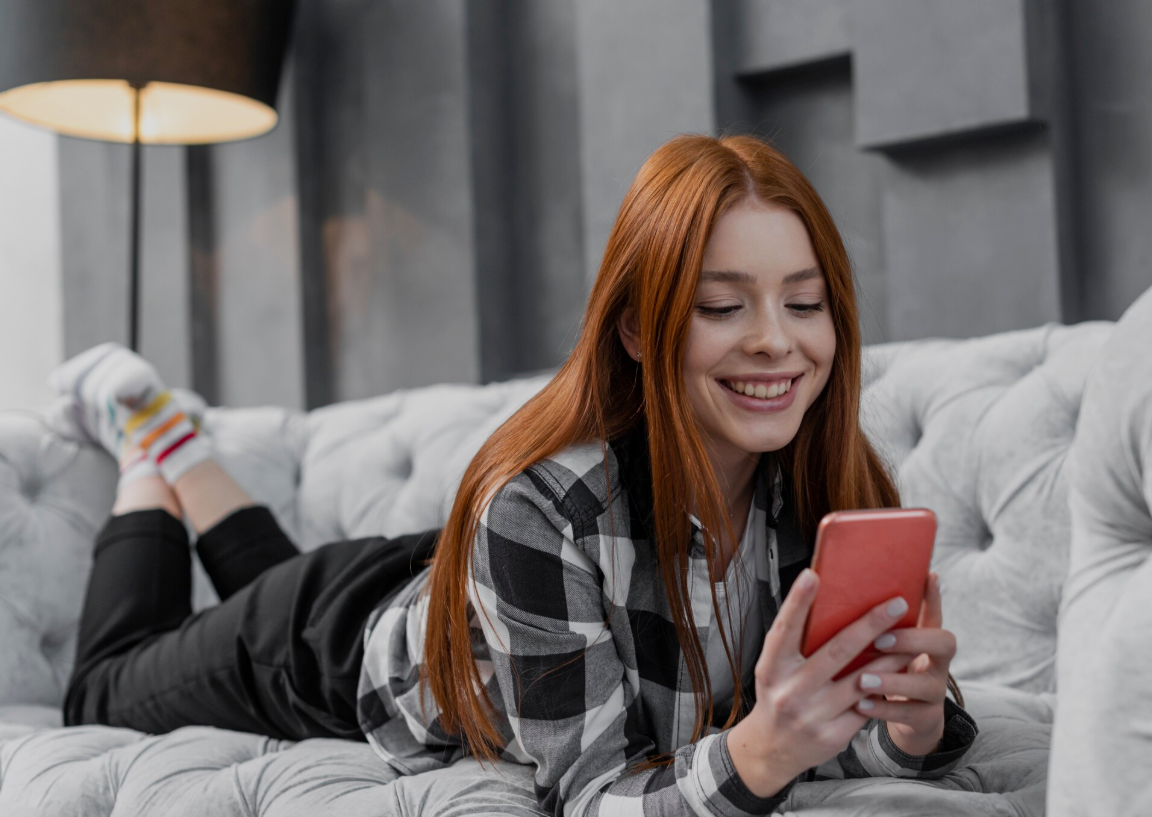 Garota ruiva jovem bela deitada no sofá usando o smartphone - criar namorado com chatgpt